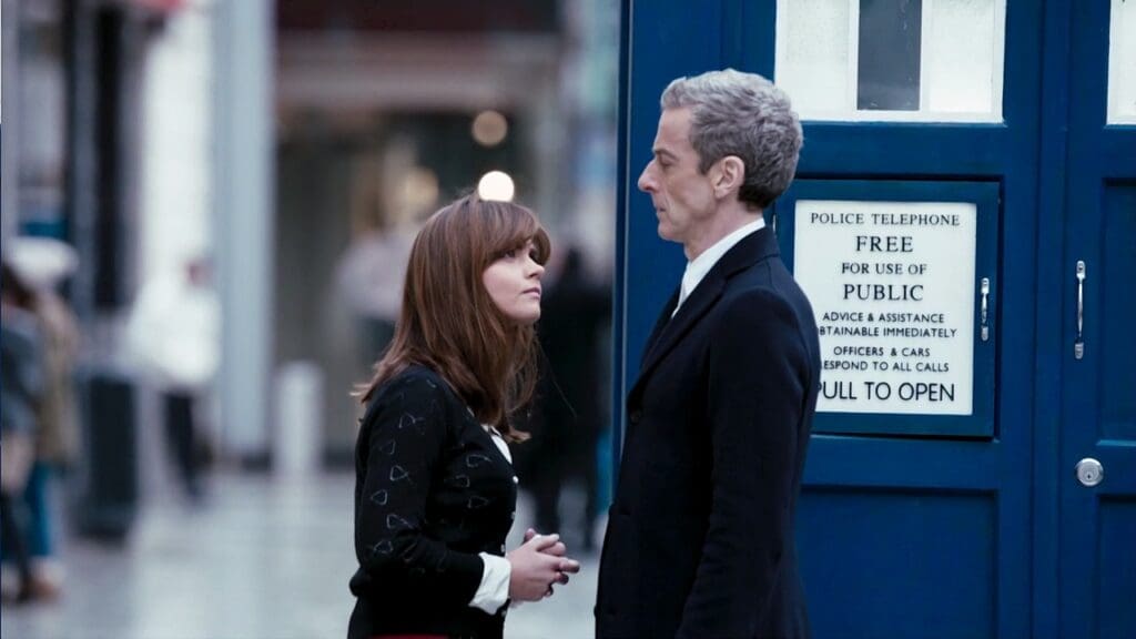 Clara, looking at the Twelfth Doctor, on a busy street, TARDIS in the background