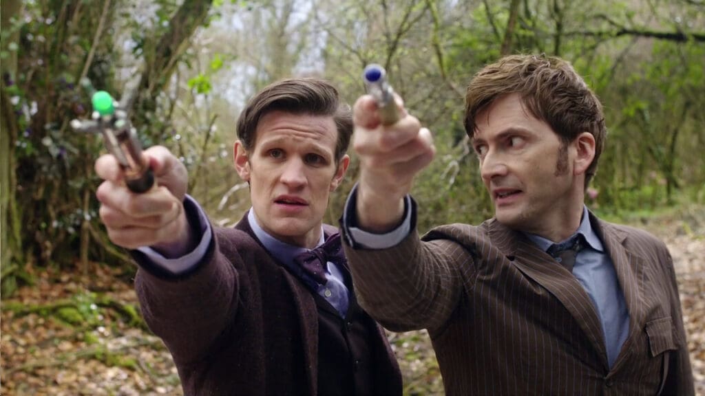 The Tenth and Eleventh Doctors, holding up their sonic screwdrivers