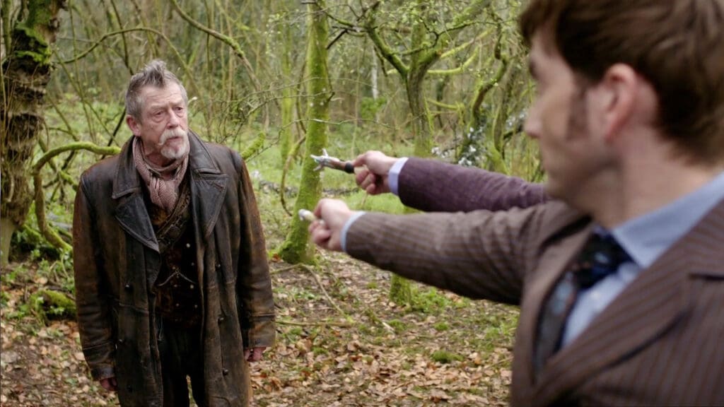 The Tenth and Eleventh Doctors pointing their sonic screwdrivers at the War Doctor
