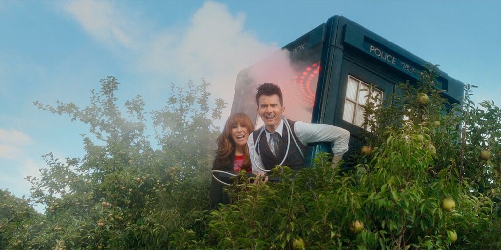 Donna and The Doctor, hanging out of the TARDIS doors which is up a tree.