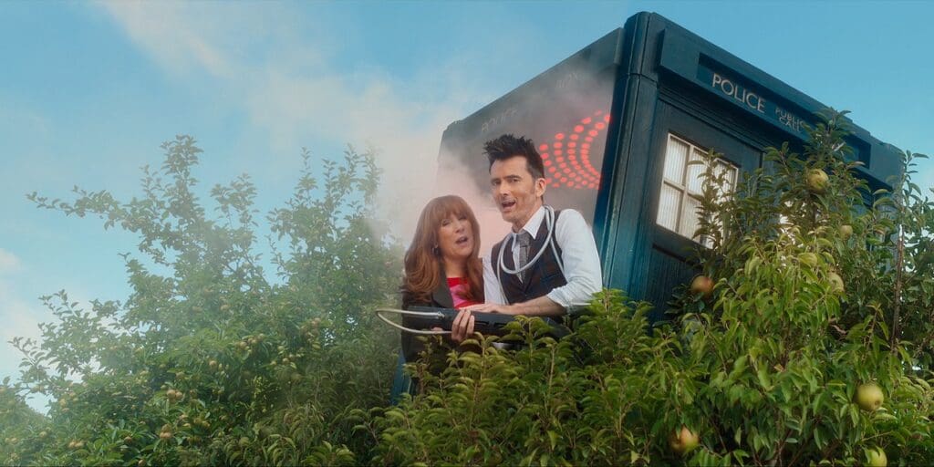 Donna and The Doctor, hanging out of the TARDIS doors which is up a tree. They are saying something in unison.