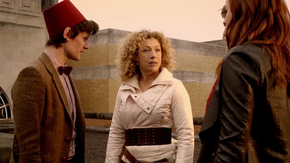 The Doctor, River, and Amy on the roof. The Doctor is wearing a fez.