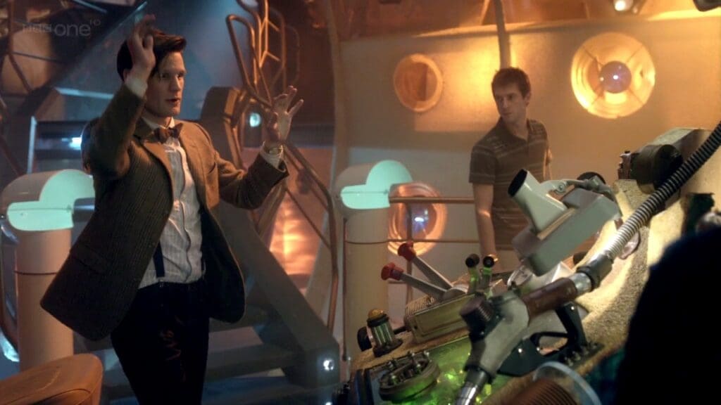 The Doctor waving his arms and being impressive in the TARDIS. Rory is in the background.