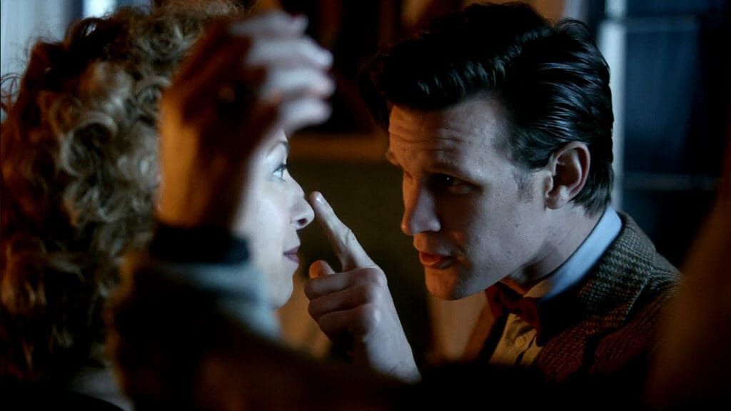 The Doctor and River, playfully flirting. River's arm is trapped by a Weeping Angel