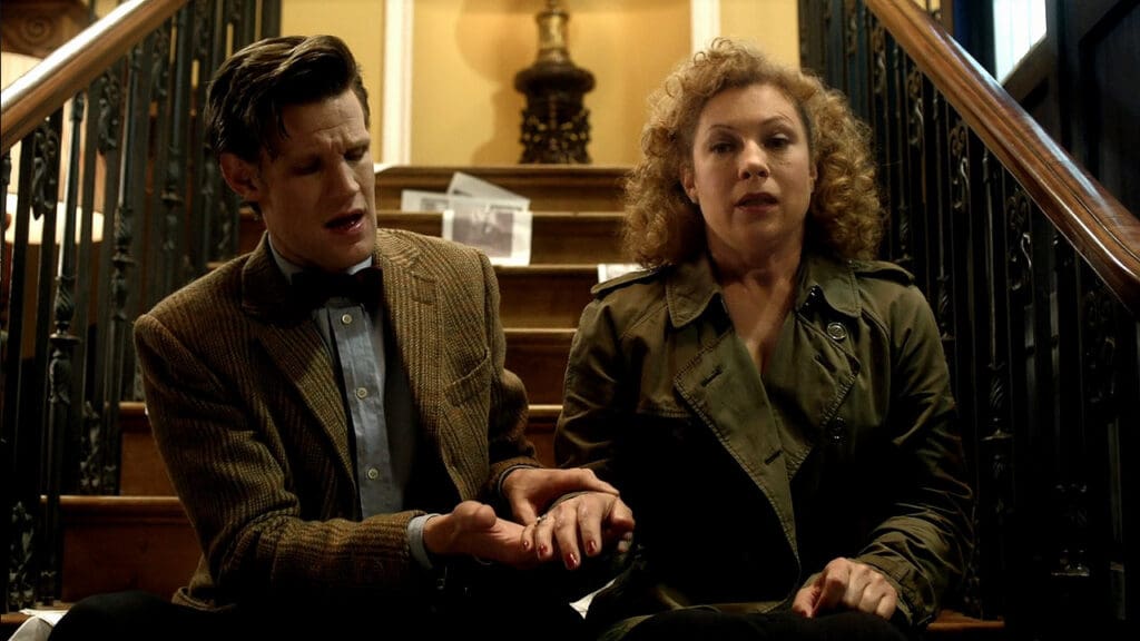The Doctor and River, sitting together on the stairs